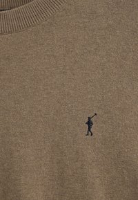 Maglione lavorato a maglia marrone con scollo rotondo a coste e un piccolo logo nero sul petto. La trama è morbida e uniforme.