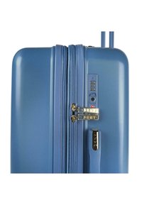 Maleta de policarbonato dura en azul con un acabado texturizado, cremalleras dobles, cerradura de combinación, detalles en dorado y un asa telescópica.