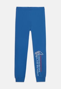Blaue Leggings aus weichem Stoff mit einem Grafikdesign eines Gaming-Controllers und dem Text "Tagsüber außergewöhnlich, nachts online" in Weiß und Rot.