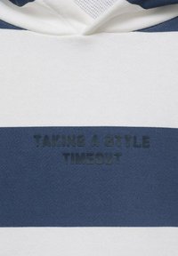 Felpa con cappuccio a righe orizzontali blu navy e bianche. Testo "PRENDIAMO UNA PAUSA STILISTICA" in lettere scure e in rilievo sulla sezione blu navy.