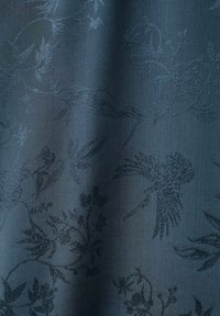 Tessuto texture in blu scuro con un sottile motivo floreale e di gru, con una superficie liscia e leggermente lucida.