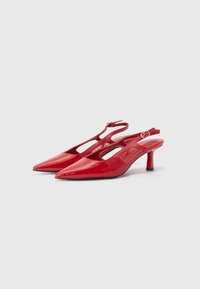 Red patent leather slingback heels with pointed toes, open sides, and a slim heel. Features an adjustable ankle strap.