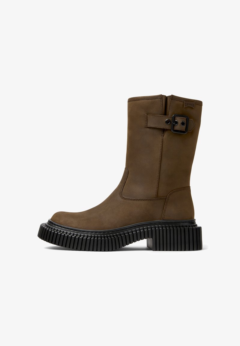 Hnědá kožená kotníková bota s kulatou špičkou, matným povrchem, bočním přezkovým detailem a strukturovanou černou gumovou podrážkou.