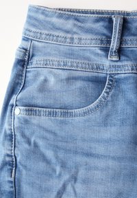 Vaaleansiniset farkut, joissa on korkea vyötärö, etutasku ja erottuva keltainen tikkaus saumoissa. Sileä rakenne.