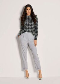 Zwart en grijs houndstooth gebreid sweatshirt gecombineerd met lichtgrijze op maat gemaakte broek. Gladde zilveren hakken, een casual maar verfijnde uitstraling.