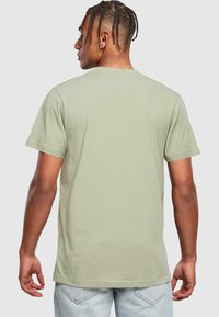 Lysegrøn t-shirt med korte ærmer lavet af blødt stof, der har et enkelt design. Bagsiden viser en lige skåret søm og minimal detaljer.