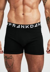 Svarta boxershorts i bomull med elastisk midjeband där varumärket "FRANK D." syns i vit typografi.