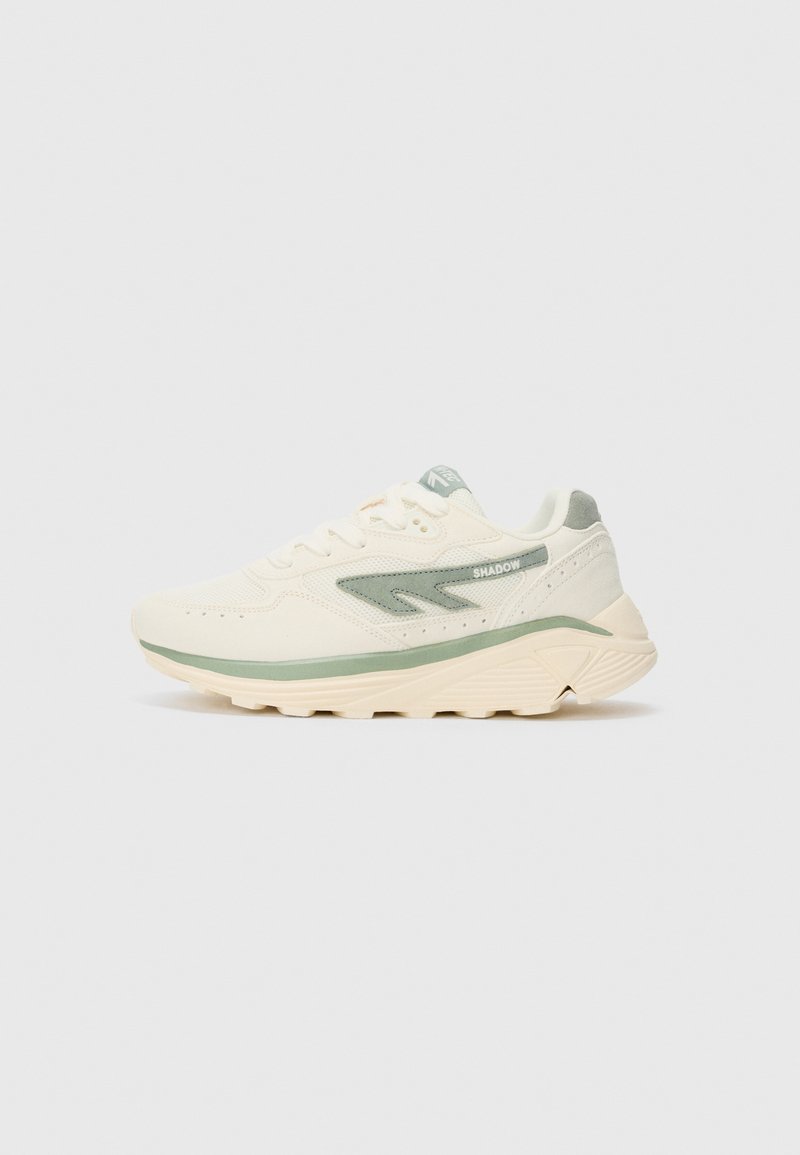 Beige and light green athletic sneaker with thick sole, mesh and suede upper, and "SHADOW" text on the side panel.