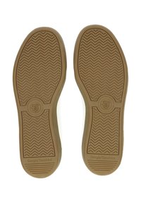 Egy edzőcipő talpa, amelyen textúrált barna gumi felület található, zig-zag mintázattal és a közepén dombornyomott kör alakú logóval.