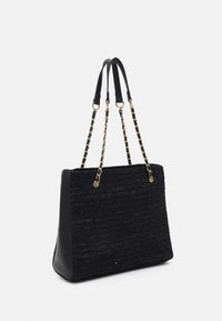 Svart texturerad tygväska med strukturerad form, utrustad med släta läderdetaljer och metalliska guldfärgade kedjeremmar. Öppen design upptill.
