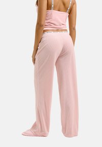 Lichtroze geribbelde tanktop met dunne schouderbandjes, gecombineerd met bijpassende wijde broek met een elastische tailleband. Zachte stof, ontspannen pasvorm.