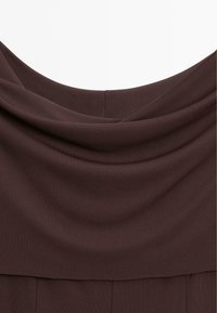 Haut à col bénitier marron avec une texture lisse, un design drapé et des plis discrets aux épaules, offrant une finition propre et tailleur.