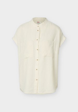 Kortermet, off-white skjorte med knappestolpe, mandarin-krage og to brystlommer foran, lagt flatt mot en hvit bakgrunn.