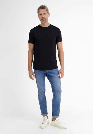 Black cotton t-shirt paired with light blue jeans and white sneakers. The t-shirt features a classic crew neck and short sleeves.