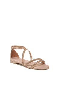 Ballet flat sandaal in nude met kruisbanden versierd met gouden details. Glad synthetisch bovenwerk en platte zool voor comfort.