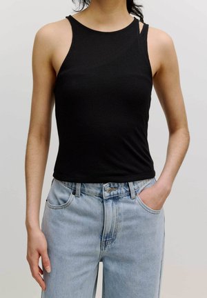 Zwarte geribbelde tanktop met een hoge halslijn en dunne bandjes, gecombineerd met lichtblauwe high-waisted denim jeans met zakken aan de voorkant.