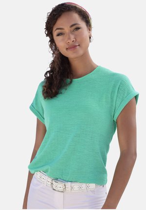 Mint green short-sleeve textured top with a round neckline, paired with white pants and a white perforated belt.