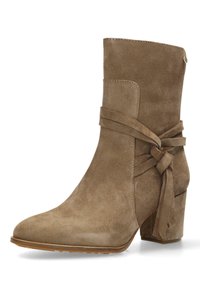 Bottine en suede marron avec un bout pointu, des détails lacés autour de la cheville et un talon bloque. Présente une texture lisse et un design minimaliste.