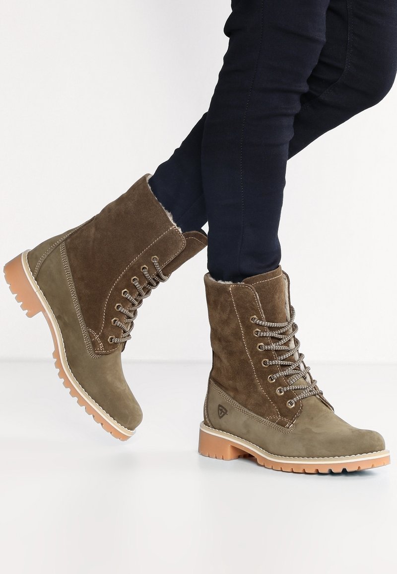 Bottes à lacets en daim marron avec une surface texturée, un col rembourré et une semelle en caoutchouc légère. Présentent des œillets métalliques et des coutures contrastantes.