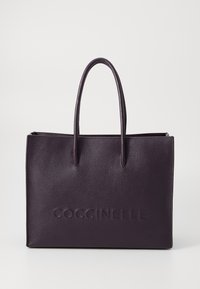 Purple leather tote bag with two long handles, embossed logo on the front, and a textured surface. Closed top with a zipper.