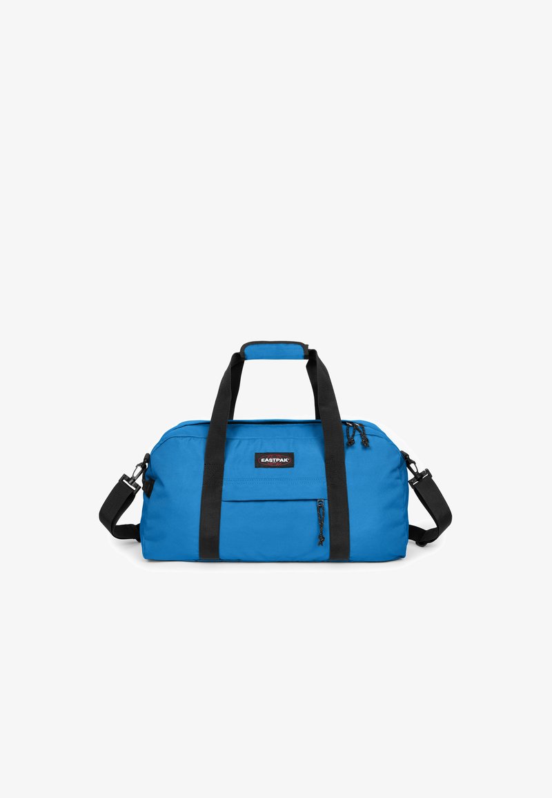 Modrá cestovní taška Eastpak s černými rukojeti, nastavitelným ramenním popruhem, přední kapsou na zip a horním uzavřením na zip.