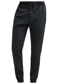 Pantalon de jogging slim gris foncé avec taille élastique, cordon noir et blanc, et chevilles resserrées.