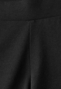 Tessuto a coste nero con una superficie liscia. Presenta una cintura elastica e un design aderente adatto per l'abbigliamento sportivo o casual.