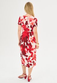 Blumenkleid mit roten Aquarellmustern auf hellem Hintergrund, knielang, mit kurzen Ärmeln, tailliert und mit einer Schleifendetail am Rücken.