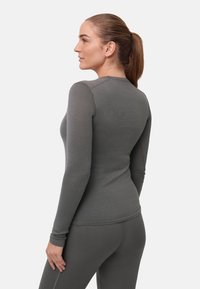 Pitkähihainen, vartalonmyötäinen harmaa paita, joka on valmistettu pehmeästä ja joustavasta kankaasta. Siinä on pyöreä pääntie ja saumaton muotoilu paremman mukavuuden takaamiseksi.