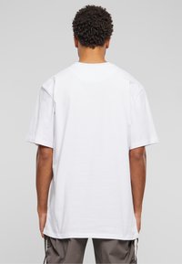 T-shirt en coton blanc à manches courtes, col rond et coupe décontractée. Couture visible le long des coutures. Pas de motifs ni de graphiques.