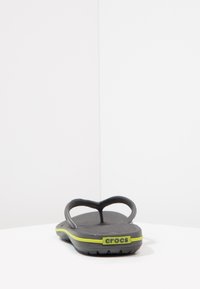 Hallitatud hallid sandaalid, millel on tekstuuriga jalatalla osa ja kaks õhukest rihma. Omab erksat kollast aksentlinti ning "crocs" logo taga.