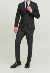 Antracytowy garnitur o slim fit. Marynarka jednorzędowa, z klapami w kształcie notcha, z zapięciem na dwa guziki. W komplecie z dopasowanymi spodniami i czarnymi butami.