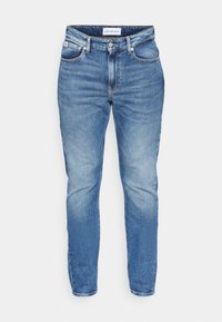 Ljusblå denimjeans med tapered fit. Funktioner inkluderar dragkedja, fem fickor och tonad söm. Slät textur och minimal blekning.