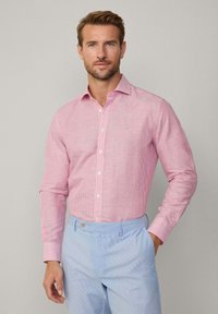 Red and white striped button-up shirt with a classic collar and long sleeves, paired with light blue striped trousers.