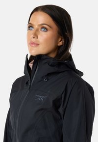 Sort vandtæt jakke med lynlås foran, justerbar hætte og diskret bjerglogo. Har et slankt design og glat tekstur.
