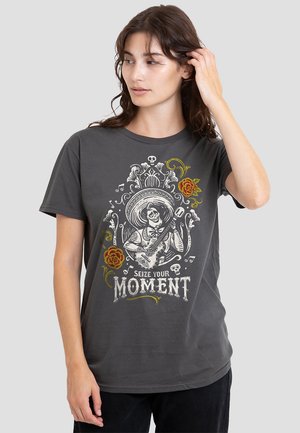Dark gray t-shirt featuring a graphic design of a skeleton playing guitar, surrounded by floral elements and text reading "SEIZE YOUR MOMENT."