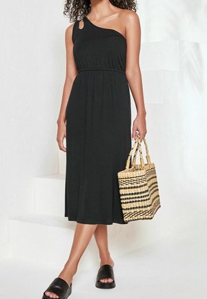 Černé šaty na jedno rameno s upnutým pasem, splývavou sukní a detailem ve tvaru klíčové dírky. V páru se pruhovanou tkanou taškou a černými sandály na ploché podrážce.