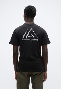 Μαύρο βαμβακερό μπλουζάκι με ασημένιο σχέδιο βουνού και το κείμενο «MOUNTAIN ATHLETICS» στην πλάτη. Κοντά μανίκια και κλασική εφαρμογή.