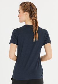 Marinblå t-shirt med kort ärm, tillverkad av mjukt, texturerat tyg, med rundad halsringning och en figurnära passform med detaljer i sid sömmen.