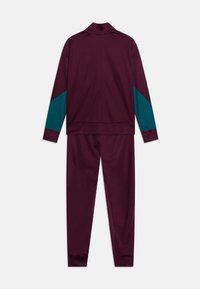 Completo sportivo bordeaux con dettagli turchesi sulle maniche. Realizzato in tessuto morbido, composto da una giacca con zip e pantaloni con fascia elastica in vita.