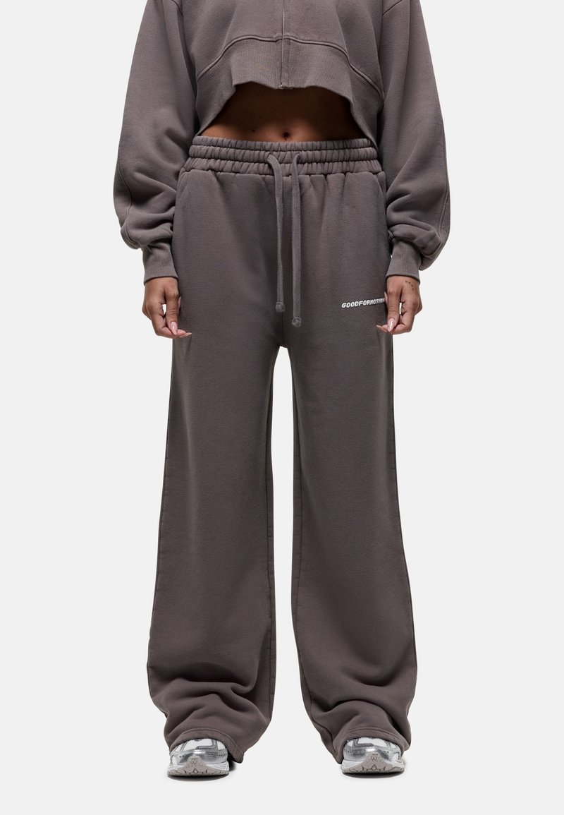 Bruine, brede sweatpants gemaakt van zachte stof met een elastische tailleband, voorzien van een trekkoord en zijlogo-detail.