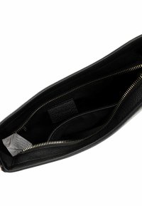 Indvendig på en sort læder clutch taske med et lynlåslomme, der har en glat overflade og en lille lap af læder. Guld lynlåsdetaile.
