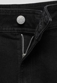 Jeans de denim negro con un cierre de botón plateado y cremallera. Vista en primer plano que destaca la textura de la tela y los detalles de la costura.