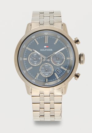 Montre-bracelet dorée avec cadran gris foncé, trois sous-cadrans pour les heures, le temps sur 24 heures, les minutes, et une fenêtre de date à 16 heures.