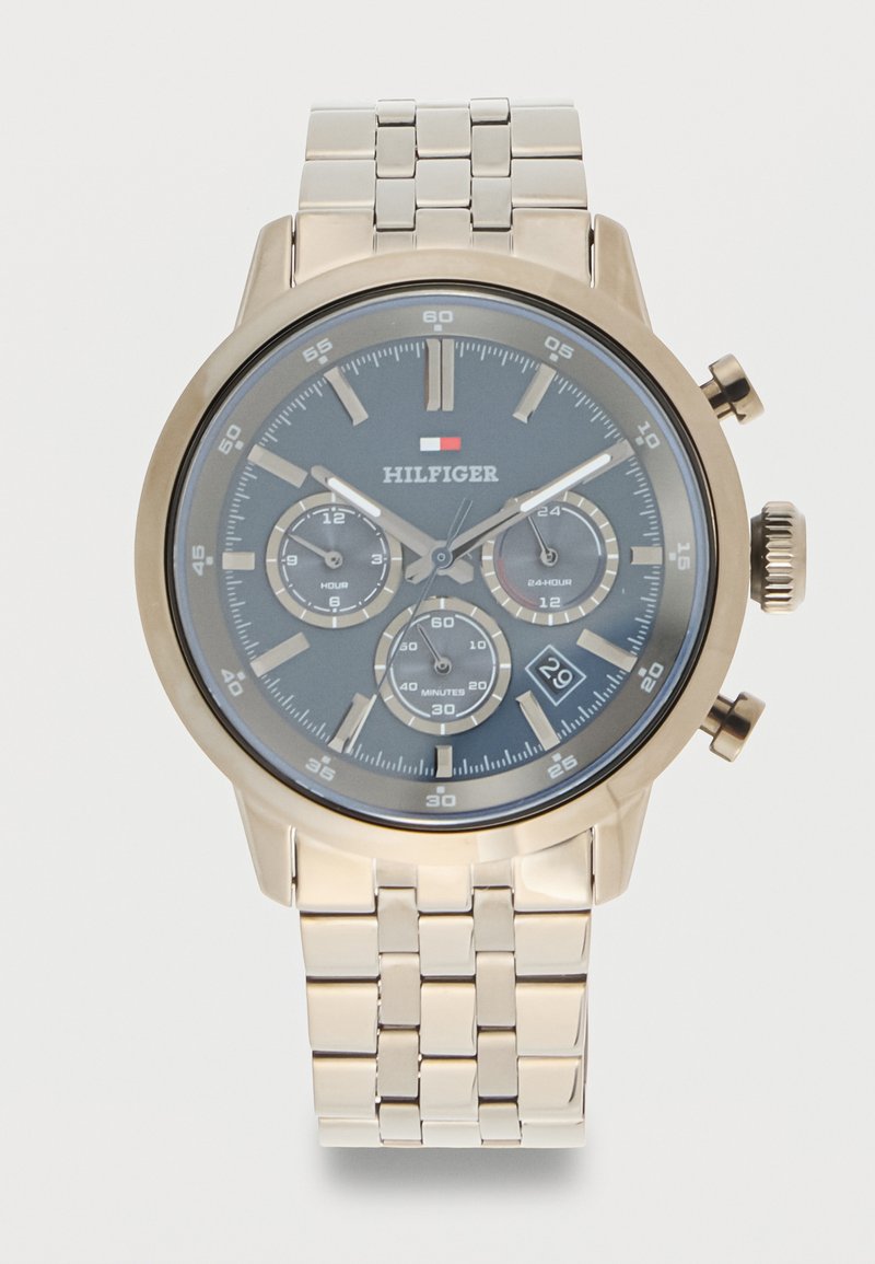 Ρολόι χειρός σε χρυσή απόχρωση με σκούρο γκρι καντράν, τρεις υποκαντράν για ώρες, 24ωρη ένδειξη, λεπτά και παράθυρο ημερομηνίας στις 4 η ώρα.