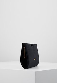 Clutch bag nera in feltro con una texture liscia. Presenta una cerniera in tono oro e un sottile dettaglio con il logo sul davanti. Forma curva.