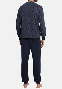 Marineblaue Schlafanzüge mit einem gemusterten Langarmshirt und einfarbigen Hosen. Weicher Stoff mit gerippten Bündchen und Bund, entworfen für maximalen Komfort.