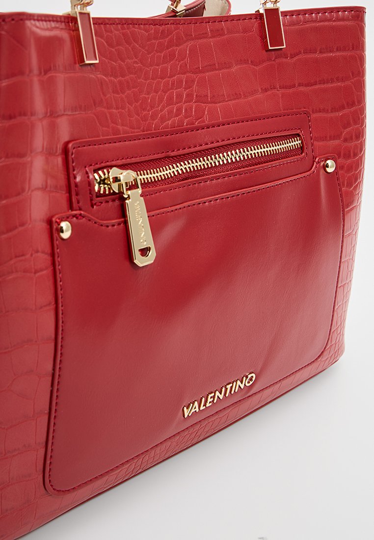 Borsa tote in finta pelle rossa con texture coccodrillo, accessori in oro, tasca con zip e logo sul davanti. Finitura liscia e lucida.