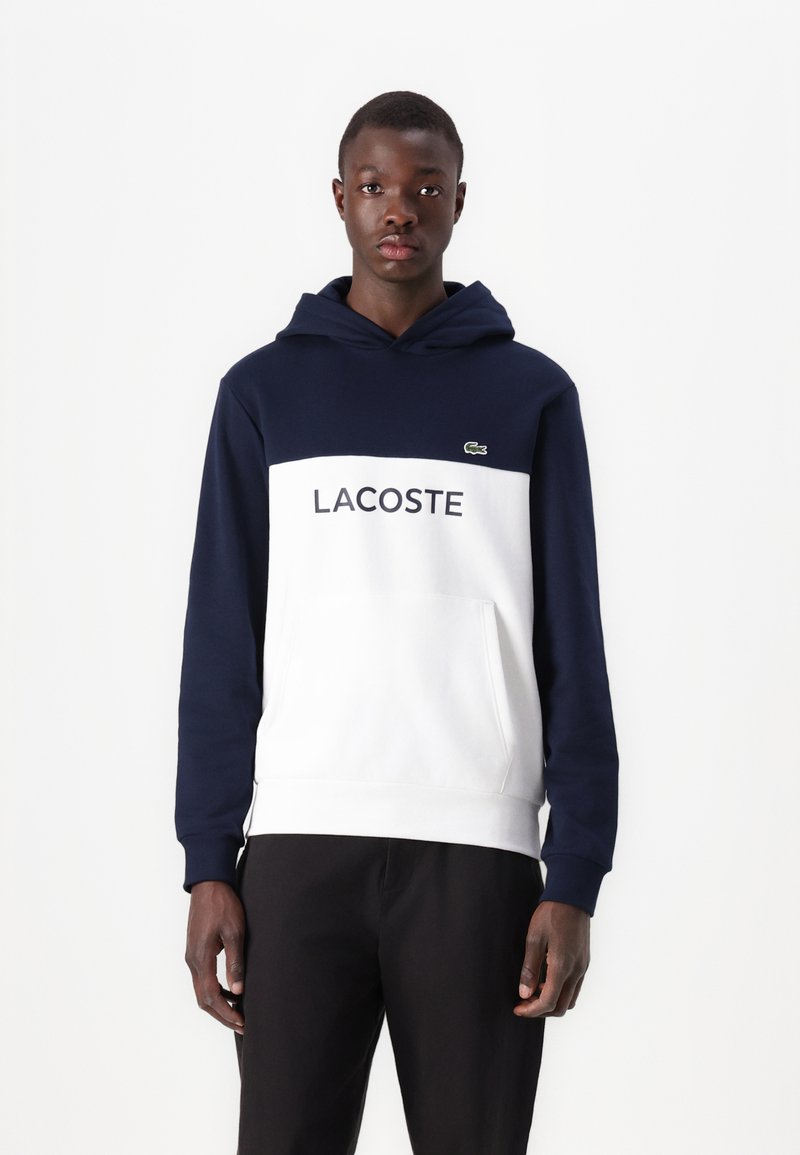Námornícky a biely farebný blokovaný mikina s kapucňou vyrobená z jemnej tkaniny, s prednou vreckom a logom "LACOSTE" na hrudi, s kapucňou na šnúrku.