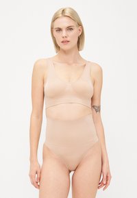 Hellbeige nahtloser Bralette und hochtaillierte Unterteile aus glattem Material, mit einem breiten Band unter der Brust und einem minimalistischen Design.